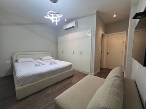 A modern bedroom with a bed, a wardrobe, a sofa, and a ceiling light fixture. - Luxury 4BR Cyan Villa • Private Pool (Hurghada 2)