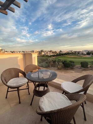 Ein Balkon mit Korbmöbeln und Blick auf einen Golfplatz.