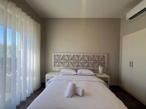 A hotel room with a bed, a bedside table, a decorative headboard, and a wardrobe.