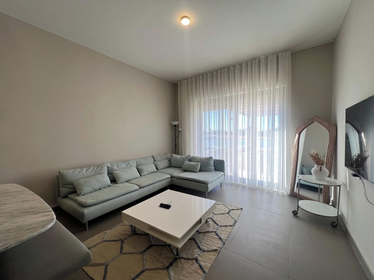 Un salon moderne avec un canapé d’angle, une table basse et un téléviseur.
