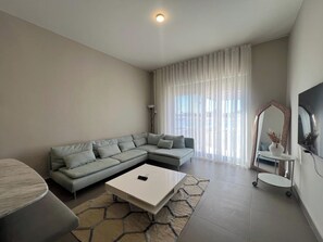 A modern living room with a sectional sofa, a coffee table, and a TV.