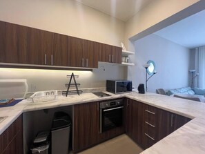 A modern kitchen with dark wood cabinets, a microwave, and a sink.