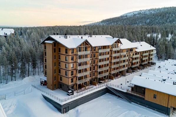 Un hôtel à plusieurs étages, doté d’une façade en bois, de balcons et surplombant un paysage enneigé.