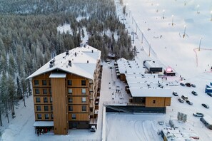 Un bâtiment en bois à plusieurs étages, avec un télésiège visible en arrière-plan.