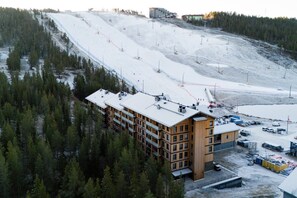 Ein mehrstöckiges Gebäude mit flachem Dach, umgeben von verschneiter Landschaft und dichtem Wald.