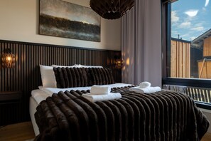 A bedroom with a large bed, a painting on the wall, and a window with a view. - Le Chalet Lingonberry D4 (Levi)