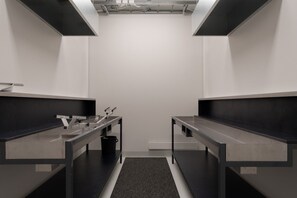 Une cuisine moderne avec deux plans de travail en acier inoxydable, une poubelle noire et un tapis noir.