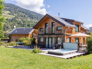 Eine Holzhütte mit Whirlpool, Sitzgelegenheit im Freien und einer Solaranlage.