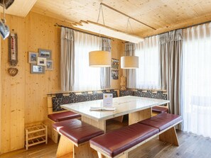 A wooden interior with a glass-top table, benches, and curtains. - One-bedroom Cabin (Sankt Georgen am Kreischberg)