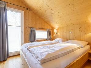 A wooden cabin room with a bed, a window with curtains, and a wall-mounted light fixture. - One-bedroom Cabin (Sankt Georgen am Kreischberg)