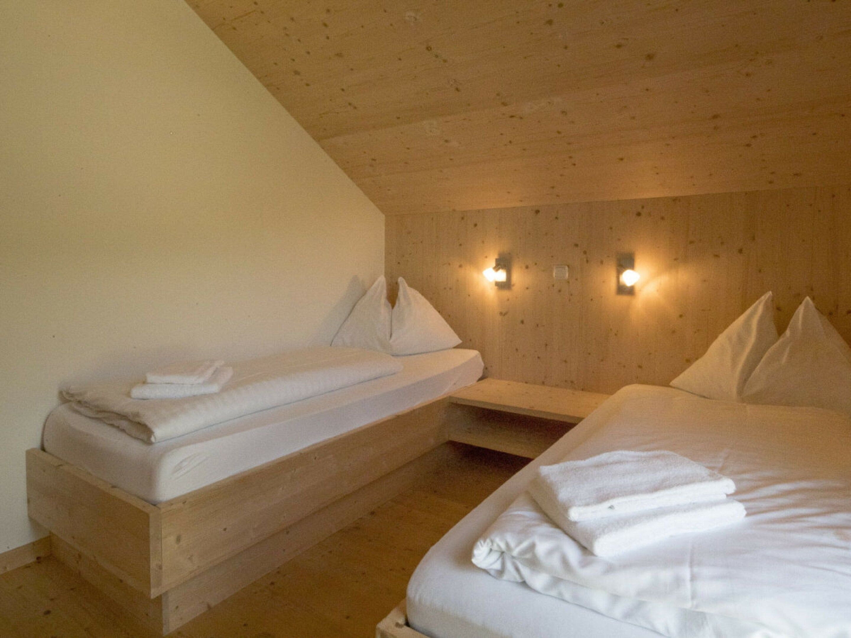 Een kamer met twee bedden, houten wanden en wandlampen.