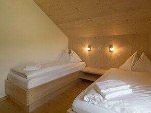 A room with two beds, wooden walls, and wall-mounted lights. - Cabin With 1 Bedroom (Sankt Georgen am Kreischberg)