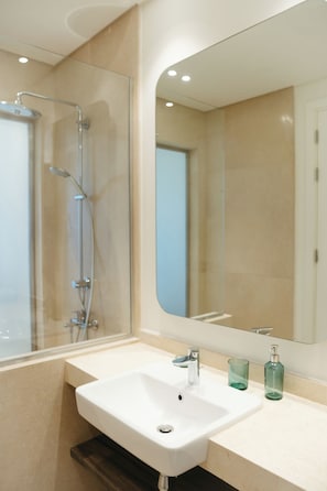 Een moderne badkamer met een wit wastafelmeubel, een douchecabine van glas en een grote spiegel.