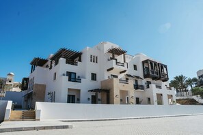 Un edificio de varios pisos con balcones, techo plano y cielo despejado.