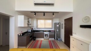 A compact kitchen with a gas stove, microwave, washing machine, and refrigerator. - Stylish G-Cribs 2BR • Pool View (EL Gouna)