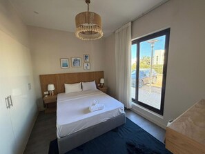 A hotel room with a bed, bedside tables, a window with a view, and a hanging light fixture. - Cyan Elegant 3BR Golf View Escape (Hurghada)