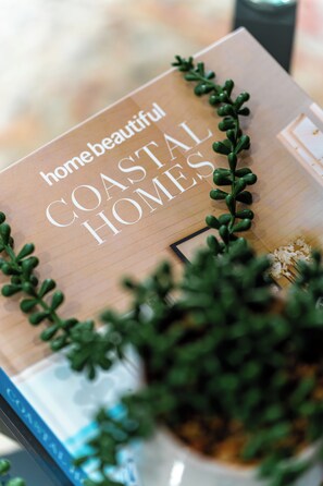 Un libro con el título 'hogares costeros hermosos', con una planta decorativa encima.