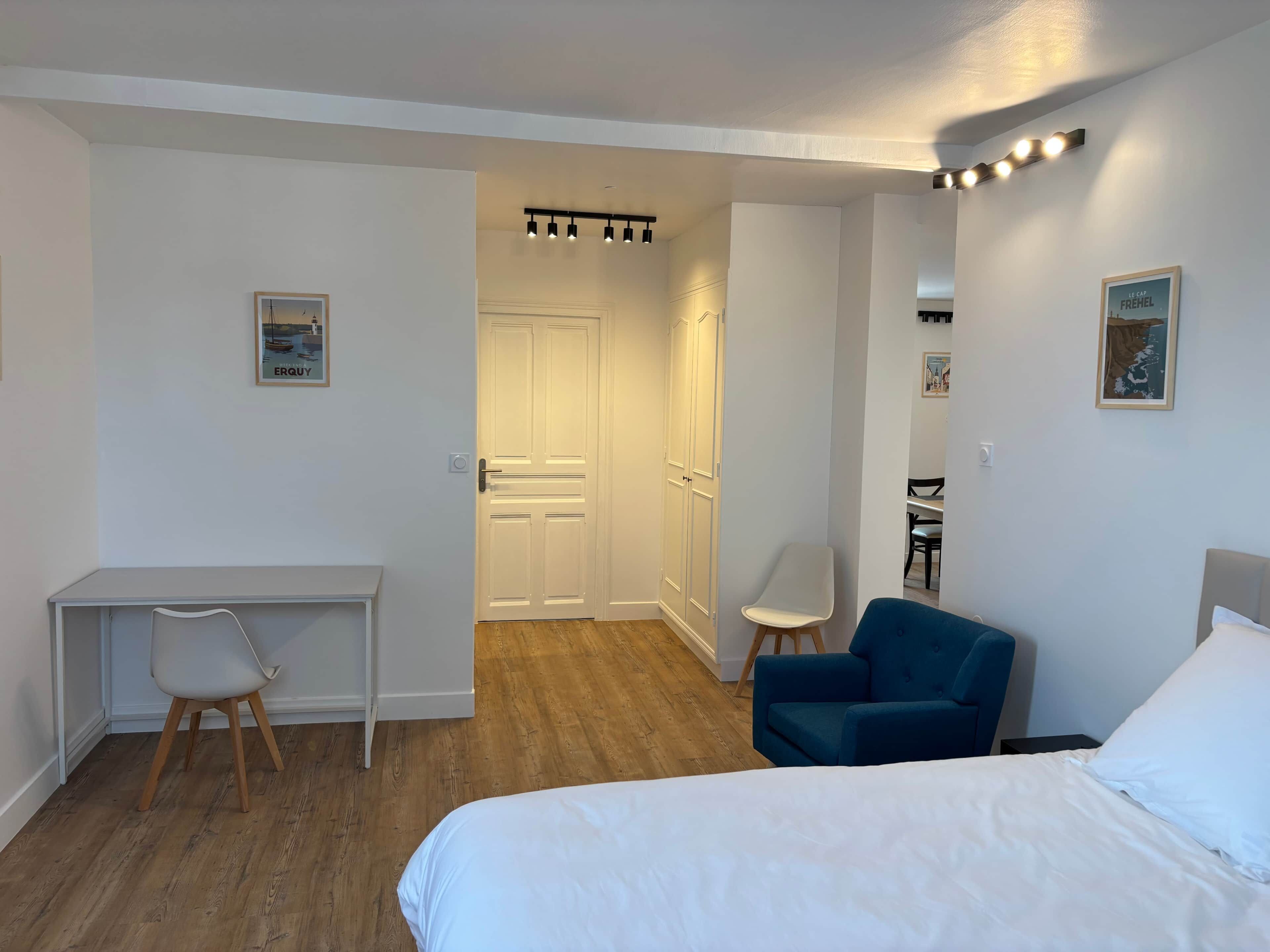 Une chambre d’hôtel avec un lit, un bureau, une chaise et une armoire.