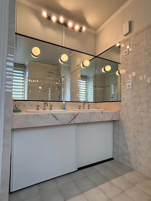 Een moderne badkamer met een grote spiegel, twee wastafels en een marmeren aanrechtblad.