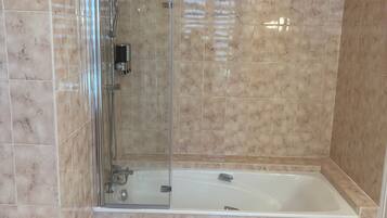 Een badkamer met een douche met glazen wand, een bad en een wastafel op een zuil.