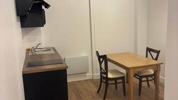 Een kleine keuken met een zwart aanrecht, een houten eettafel en twee stoelen.