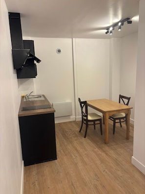 Cozinha compacta com bancada preta, mesa de madeira e duas cadeiras.