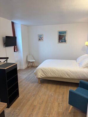 A bedroom with a bed, a desk, a chair, and a TV mounted on the wall. - TYYANN 8: A 26-square-meter studio equipped with a kitchenette and a bathroom (Plancoët)