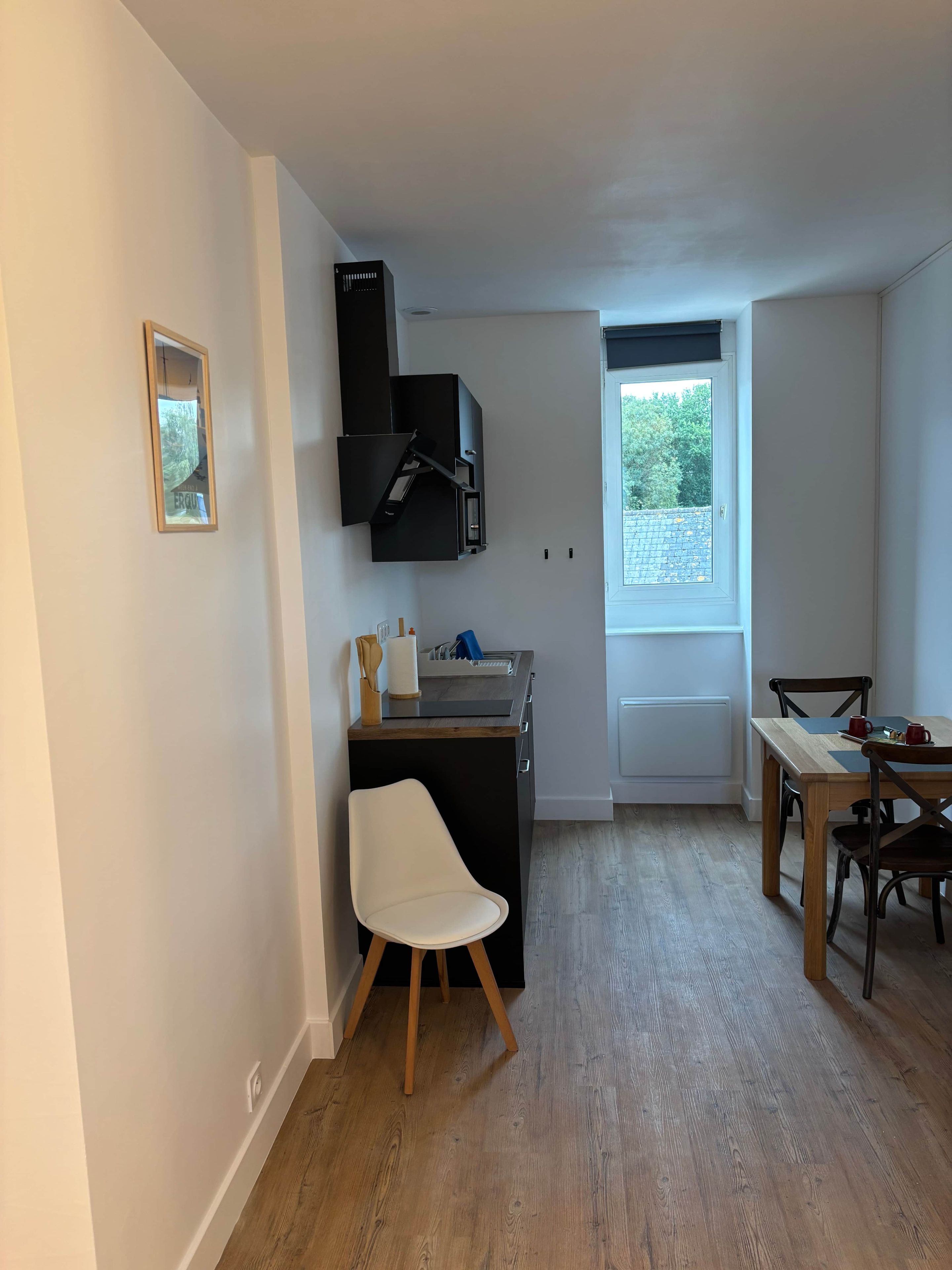 Een compacte keuken met een inbouwfornuis, een eethoek met een tafel en stoelen, en een raam dat voor daglicht zorgt.