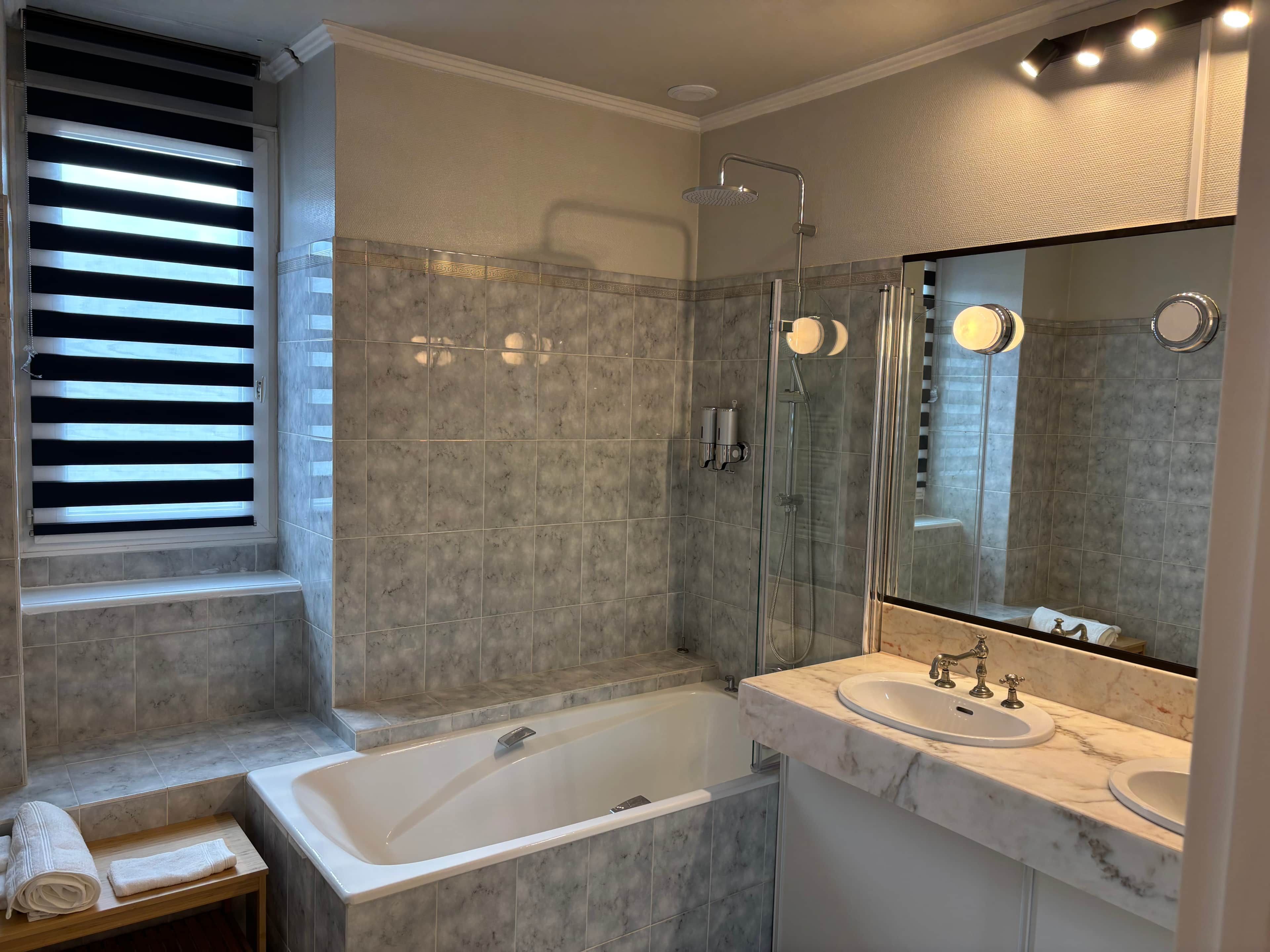 Ein modernes Badezimmer mit Badewanne, einer begehbaren Dusche und einem Waschtisch mit großem Spiegel.