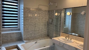 A modern bathroom with a bathtub, a glass-enclosed shower, and a vanity with a large mirror. - TYYANN 9: A 30-square-meter studio equipped with a kitchenette and a bathroom (Plancoët)