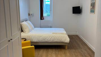 Ein Schlafzimmer mit einem Bett, einem Fenster, einem Fernseher und einer Tür.