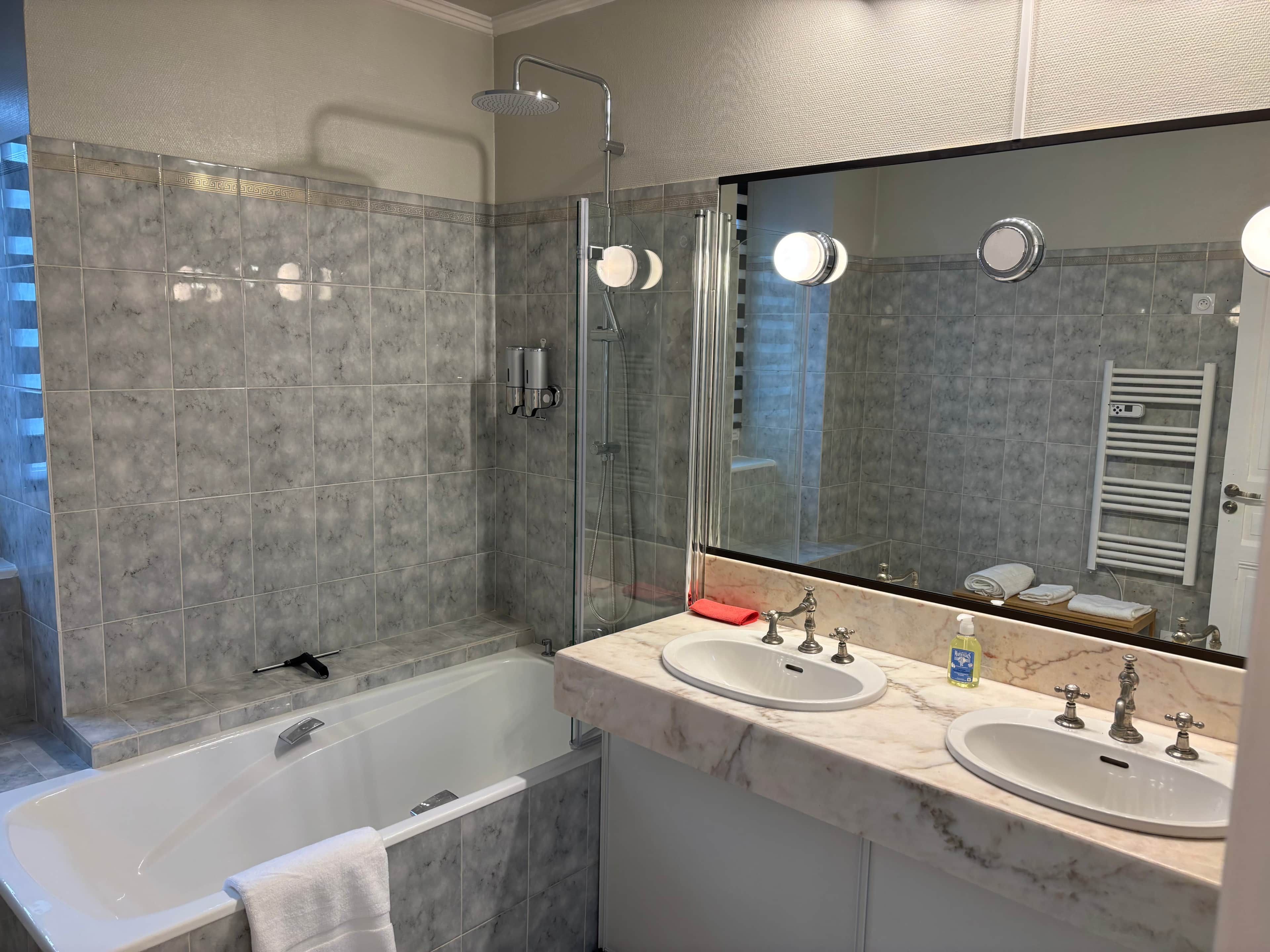 Une salle de bain moderne avec une baignoire, deux lavabos et un grand miroir.