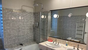A modern bathroom with a bathtub, two sinks, and a large mirror. - TYYANN 9: A 30-square-meter studio equipped with a kitchenette and a bathroom (Plancoët)