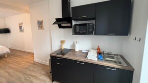 Cozinha moderna com armários pretos, micro-ondas e pia de aço inoxidável.