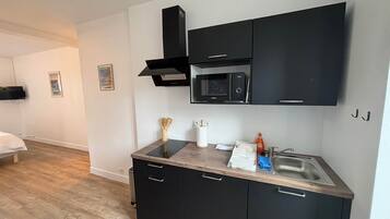 A modern kitchen with black cabinets, a microwave, and a stainless steel sink.