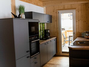 A modern kitchen with a built-in oven, a coffee machine, and a view of the outside. - Cabin With 1 Bedroom (Sankt Georgen am Kreischberg)