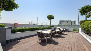 An outdoor patio with wooden flooring, outdoor seating, and a view of the cityscape. - Studio w/ Community View,Near Meydan Golf Club, Approx 15Min Drive to Downtown (Dubai)