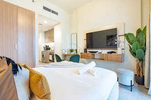 Une chambre d’hôtel moderne équipée d’un lit, d’un bureau, d’une machine à laver et d’un téléviseur.