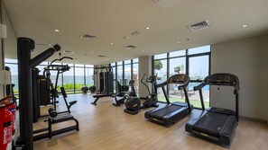 Une salle de sport équipée de machines de cardio, de matériel de musculation et offrant une vue sur l’extérieur.