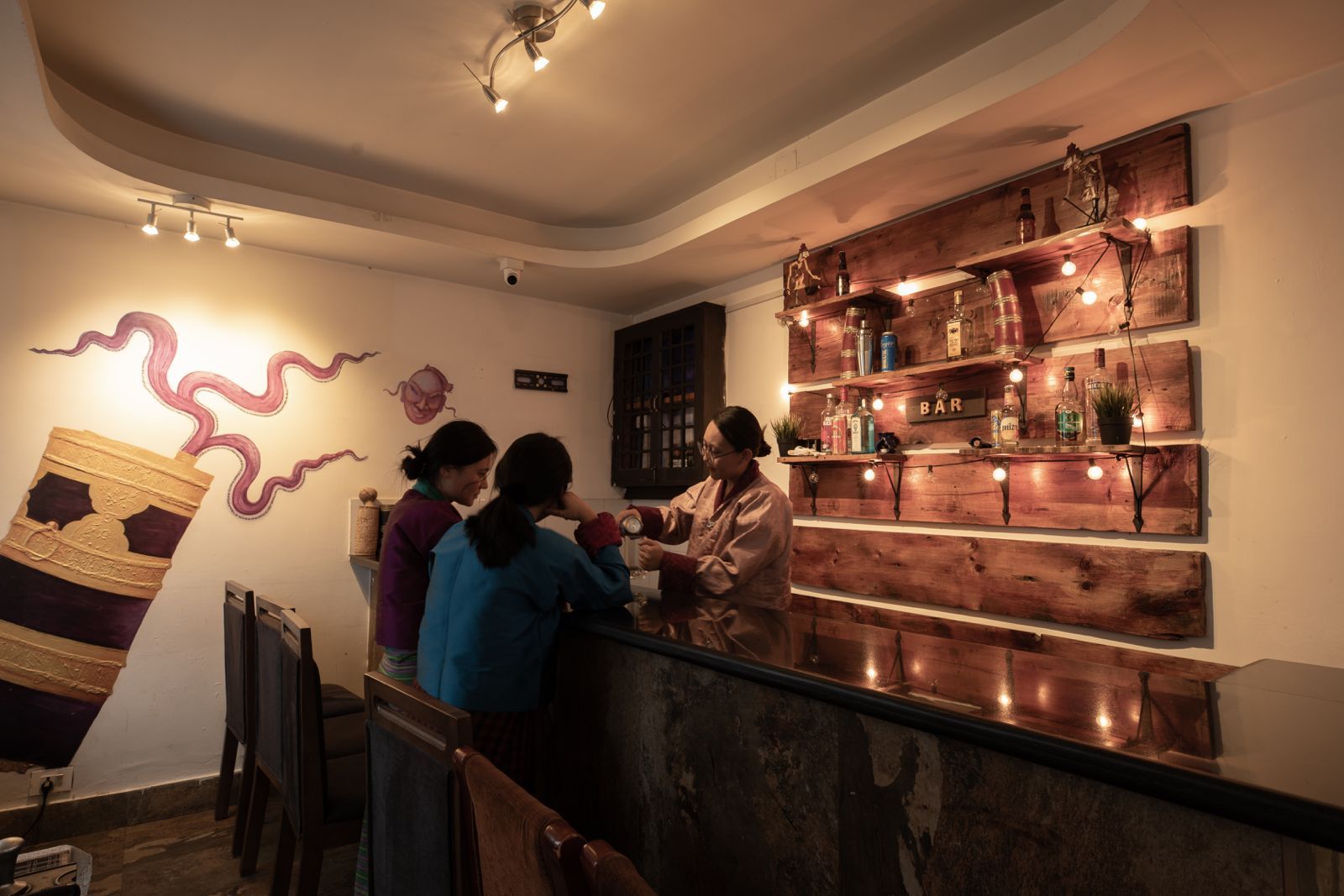 Zona de bar con estanterías de madera que exhiben botellas y un cartel que dice 'BAR'.