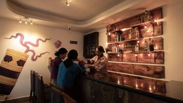 Zona de bar con estanterías de madera que exhiben botellas y un cartel que dice 'BAR'.