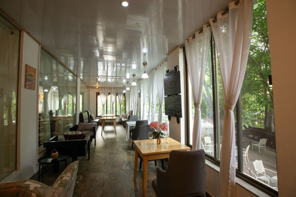 A dining area with a long table, chairs, and a view of the outdoors.