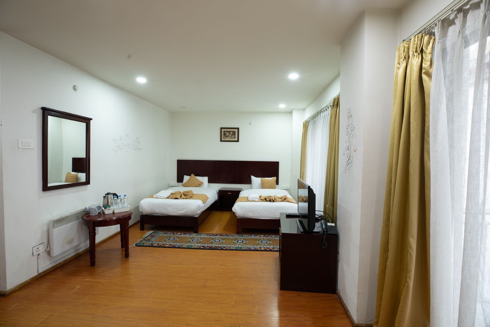 A hotel room with two beds, a desk, a chair, a television, and a window with curtains.