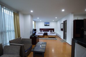 A hotel room with a bed, a TV, a desk, and a seating area.