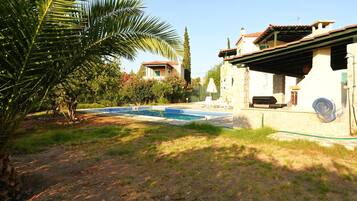Ein Wohnhaus mit Swimmingpool, Terrassenbereich und Garten mit einer Palme.
