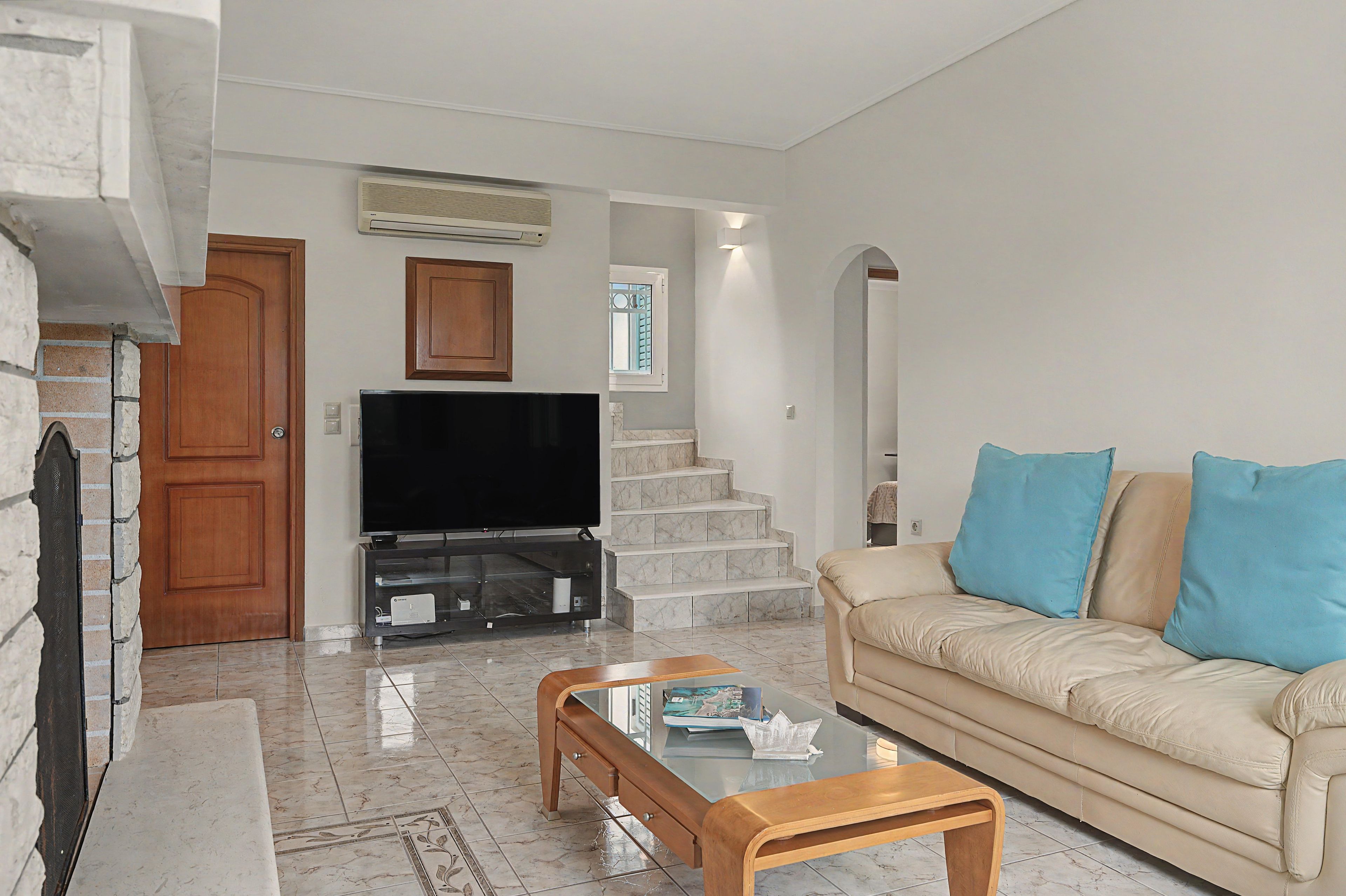 A living room with a television, sofa, coffee table, and a staircase leading to another level.