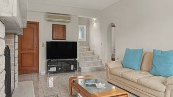 A living room with a television, sofa, coffee table, and a staircase leading to another level.
