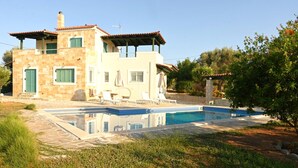 Ein zweistöckiges Haus mit Swimmingpool, Sitzgelegenheiten im Freien und einem Garten.