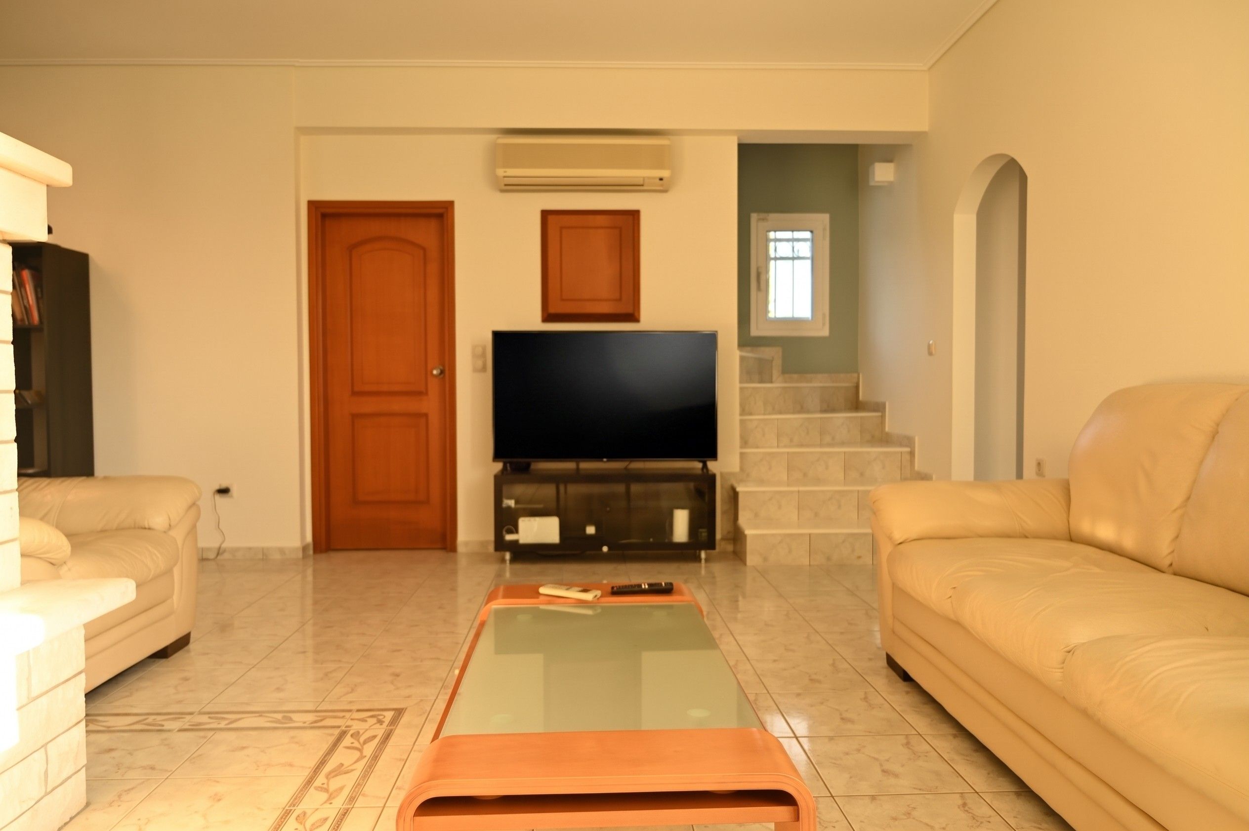A living room with a television, sofa, and a glass coffee table.