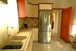 A kitchen with a stainless steel refrigerator, a sink, and a tiled backsplash.